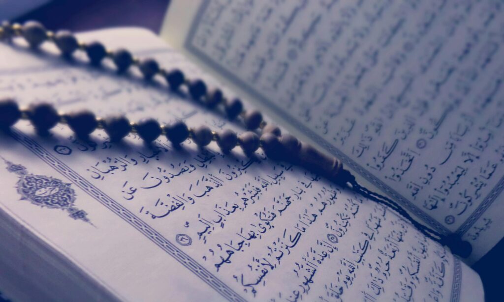 pexels-photo-318451-318451 A close-up of prayer beads resting on an open Quran page, depicting Islamic faith and worship.