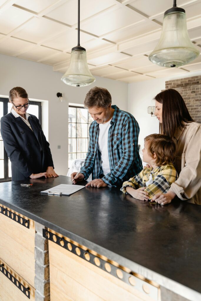 pexels-photo-7415115-7415115 Family with a child signing a real estate agreement in a bright, modern kitchen with a realtor.