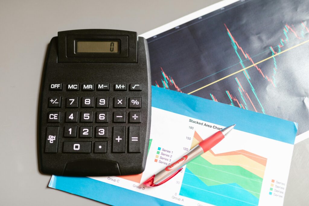 Calculator and pen on a desk with financial charts, showcasing analysis and business planning.
