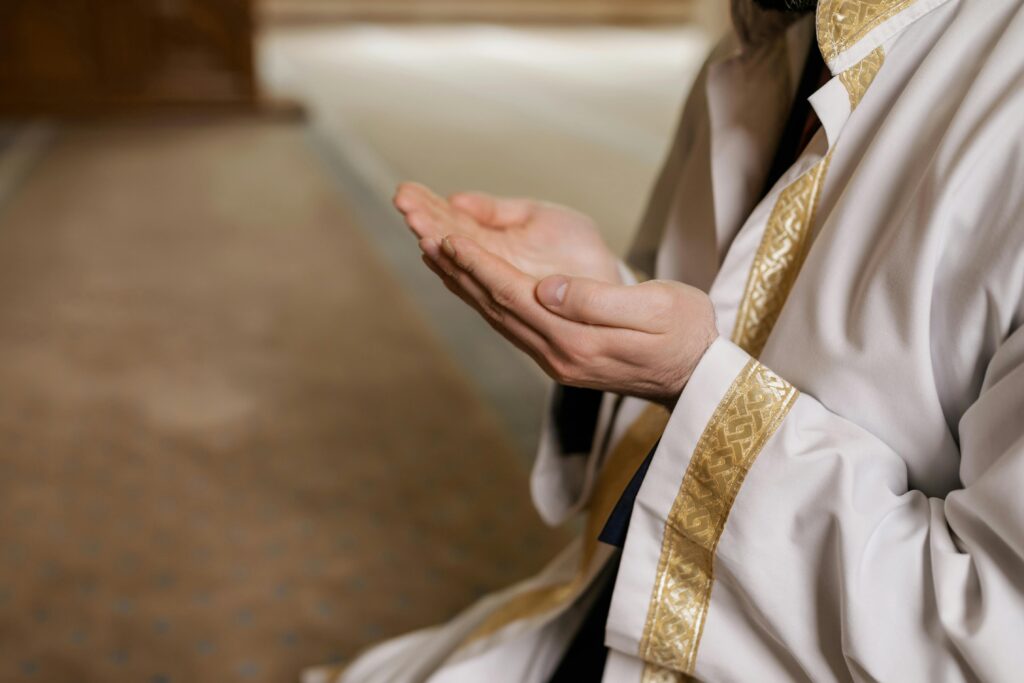 pexels-photo-8164382-8164382 A man in traditional Middle Eastern attire prays indoors, hands clasped together.