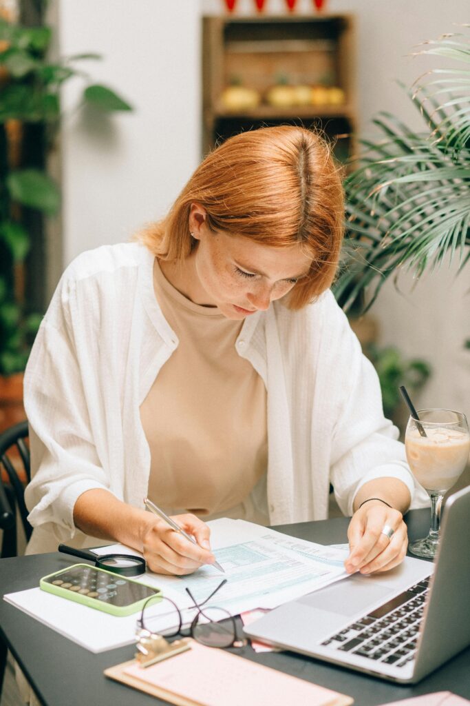 pexels-photo-8927463-8927463 Woman analyzing financial documents using laptop and calculator indoors.