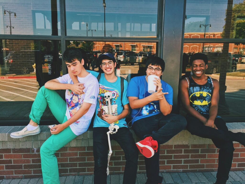 pexels-photo-923657-923657 Group of teenage friends sitting outdoors, smiling and having fun together.