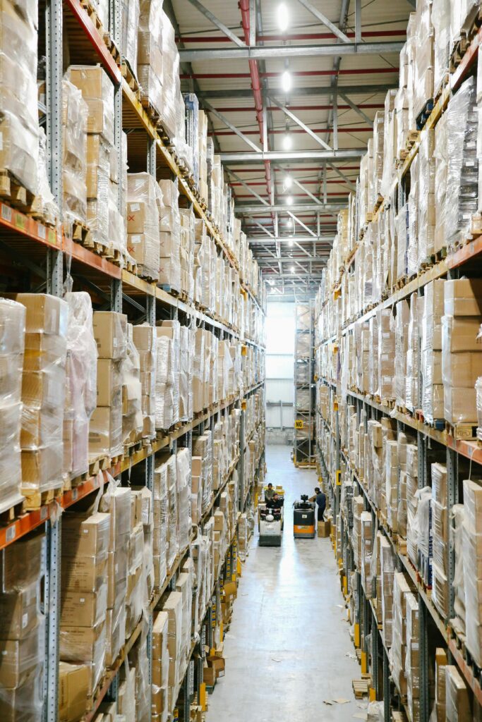 pexels-photo-5156696-5156696 Spacious warehouse aisles lined with shelves stacked with boxes and packaging.