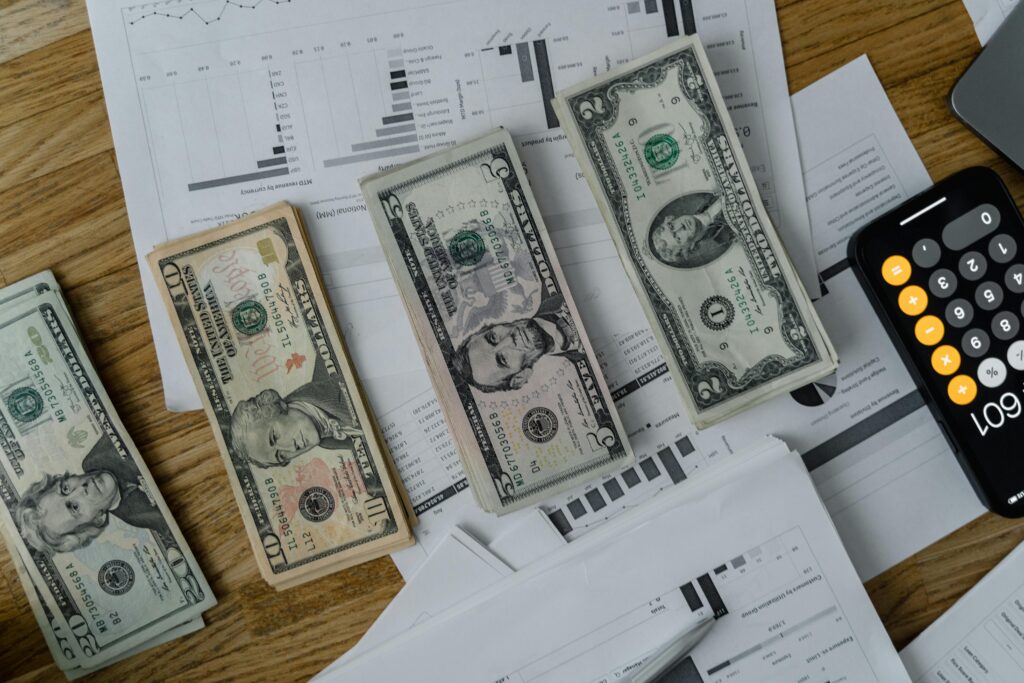 pexels-photo-6693665-6693665 A workspace setup featuring cash, documents, and a calculator symbolizing financial analysis and budgeting.