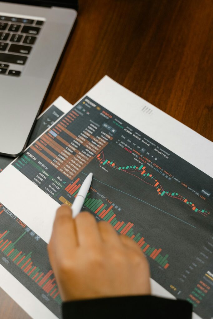 pexels-photo-7567224-7567224 Close up of a person analyzing cryptocurrency graphs on printed charts.