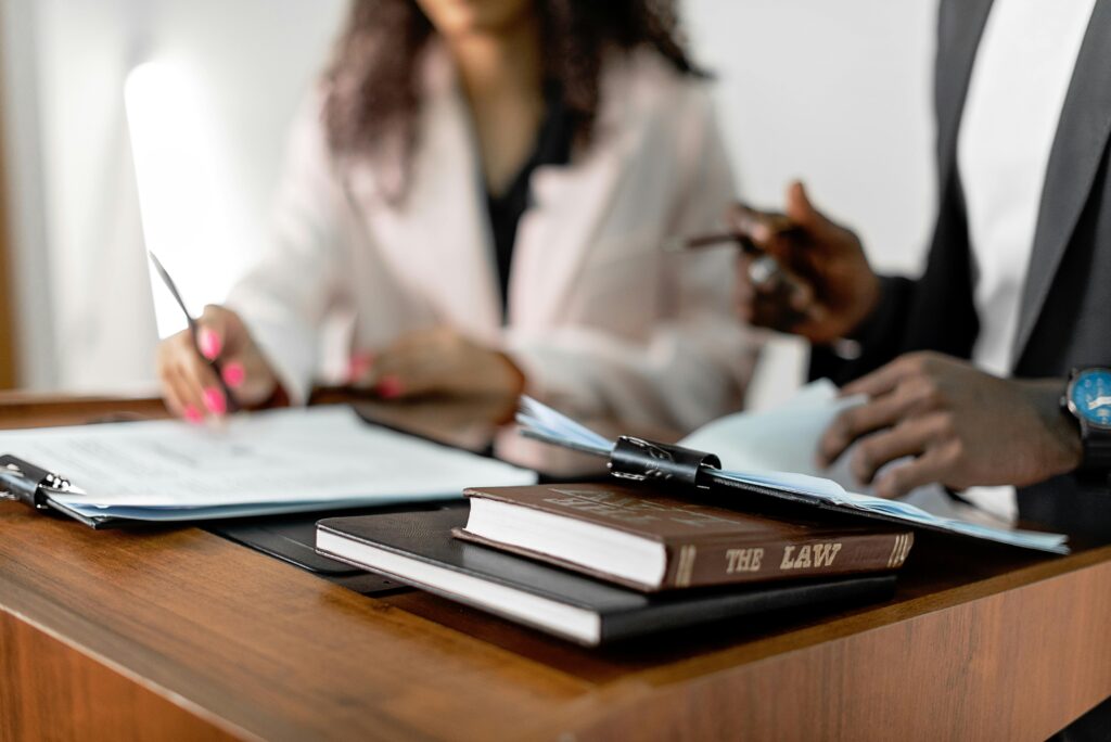 pexels-photo-8730785-8730785 Two lawyers reviewing documents with law books on a desk. Professional legal environment.